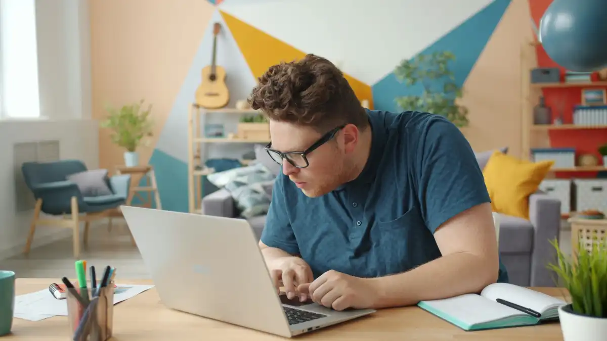 Cheerful person attractive guy is having fun working with laptop